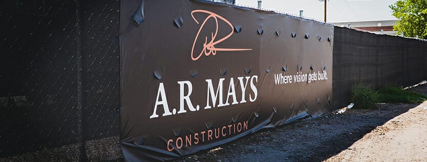 vinyl banner with wind slits installed at construction job site with graphics showing A.R. Mays Construction logo