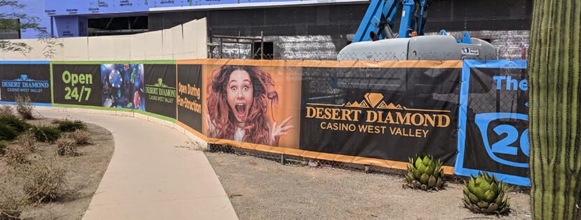 fence mesh banner installed at construction job site with graphics featuring desert diamond casino