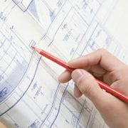 Person with a pencil looking over a blueprint