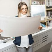 Young woman standing at a printing looking over a printed project.