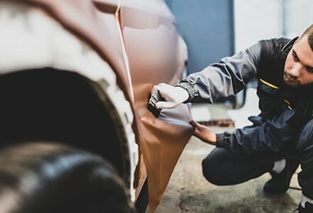 Man installing a printed vehicle wrap on a car