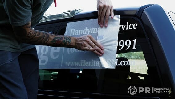 Person applying printed window graphics to a vehicle window