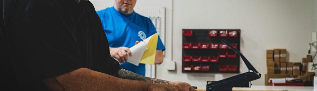 2 men talking behind the scenes at a printing company.