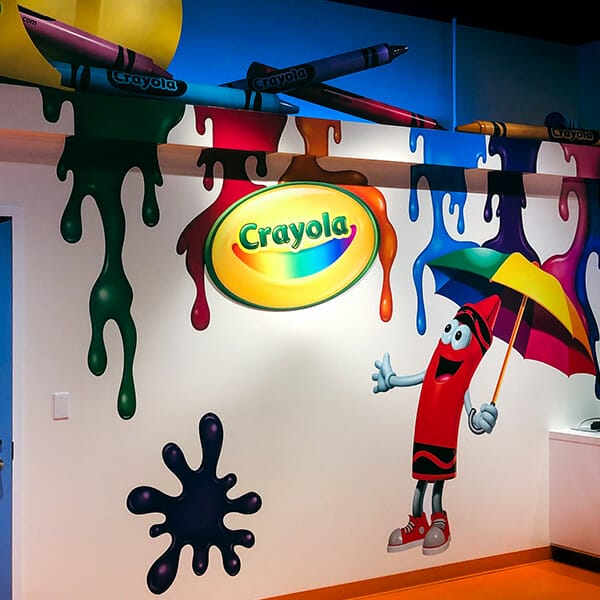 Printed wall graphics for Crayola showing crayons melting and an animated crayon character with umbrella.