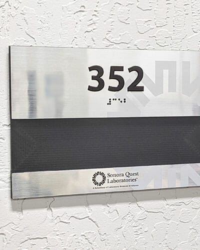 Office placard for Sonora Quest Laboratories with texture printed room number and braille.