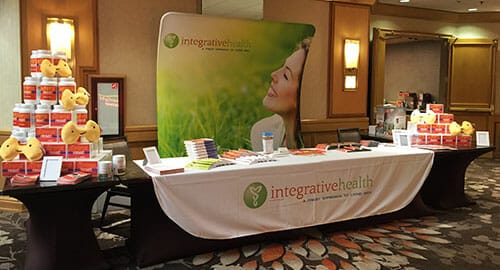 Trade show table set up and background fabric display for Integrative Health.