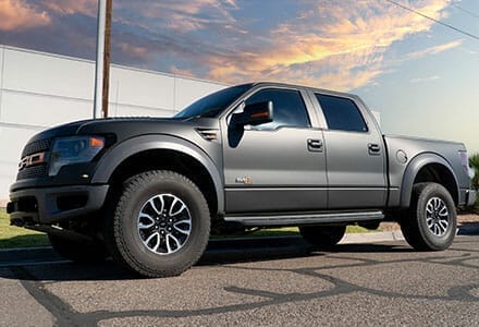 Color-change wrap of 2023 Ford Raptor from desert sand to matte black with orange accents.