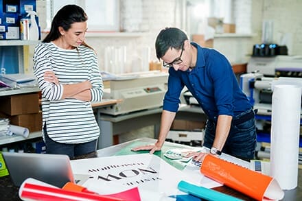 a man and a woman looking at colors for recently printed posters