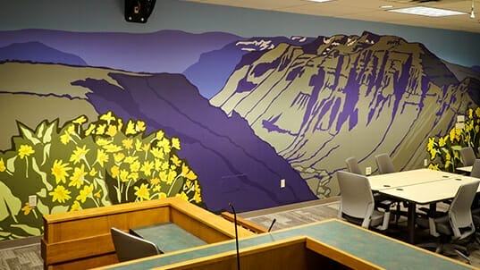 Colorful artwork of a mountain scene is installed as a wall covering.