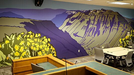 Colorful artwork of a mountain scene is installed as a wall covering.